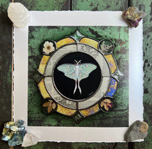 Load image into Gallery viewer, Luna moth medallion print. Luna moth is in central circle on black background with segmented border of vintage book pages. Third and outermost rung is gold mirror with bronze flecks, pressed wildflowers, and glass bevels in alternating border. 8x8" reproduction giclée print of Vintage Luna with a 1.25" deckled edge border