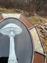 Load image into Gallery viewer, Alternate angle in bright indirect light, shows bevel in center oval. Painted white porcelain fungus on black background in center with alternating amber glass and clear glass with floral inclusion border. Gouache on paper with pressed gypsophila and maidenhair fern set between glass, with amber glass.