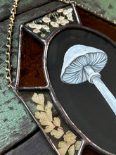 Load image into Gallery viewer, Close up with dark backdrop - Painted white porcelain fungus on black background in center with alternating amber glass and clear glass with floral inclusion border. Gouache on paper with pressed gypsophila and maidenhair fern set between glass, with amber glass.