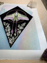 Load image into Gallery viewer, Bottom angle of print to show shimmer and colors of iridized glass on print. Full view - print on paper of Chinese moon moth and meadowsweet on black background, diamond shape. This sits in a white iridized glass background. There is a gold circle around the center of the moon moth. Meadowsweet flower painted below and surrounding moths lower wing tendrils.