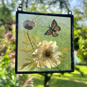 Monarch butterfly painted in gouache on paper with pressed Japanese anemone with textured clear glass backing Square shaped artwork with gold hanging chain.