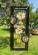 Load image into Gallery viewer, Wild grasses and daisies encased in glass with dark green glass borders segmented by two gouache monarch paintings  encased in clear glass circles. Rectangle shape with brass hanging chain at top. Center glass is clear.
