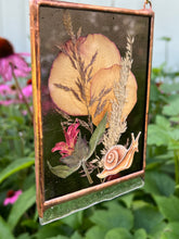Load image into Gallery viewer, Alternate angle - Painted snail in gouache on paper with ressed rose petals, bee balm, and wild grasses with dark purple glass backing and glass end on bottom to mimic SNAIL SLIME. Rectangle shape with gold hanging chain.
