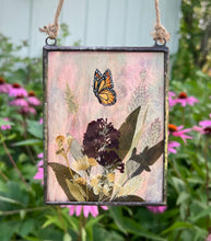 Load image into Gallery viewer, Painted monarch butterfly in gouache on paper with pressed butterfly bush flower, aster, and wild grasses with iridescent wispy pink glass backing. Rectangle shape with twine hanging.
