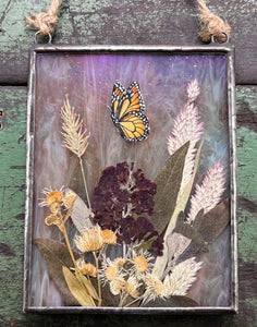 Another full view - Painted monarch butterfly in gouache on paper with pressed butterfly bush flower, aster, and wild grasses with iridescent wispy pink glass backing. Rectangle shape with twine hanging.