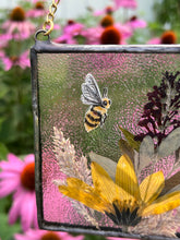 Load image into Gallery viewer, Close up of painted bee. Honeybee painted in gouache on paper with wildflower grasses and  yellow sunflower and butterfly bush with clear textured glass backing. Square shape with gold chain hanger.
