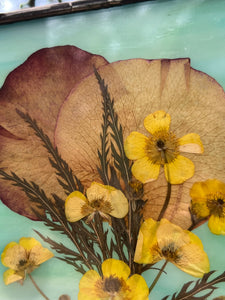 Close up of flowers - Spring buttercups, rose petals, lace leaf maple with dark wispy green/blue glass backing