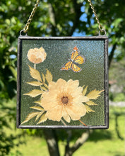 Load image into Gallery viewer, Alternate view with more light sun on piece. Monarch butterfly painted in gouache on paper with pressed Japanese anemone with textured clear glass backing Square shaped artwork with gold hanging chain.
