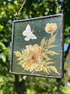Back view of piece showing clear textured glass. Monarch butterfly painted in gouache on paper with pressed Japanese anemone with textured clear glass backing Square shaped artwork with gold hanging chain.