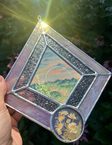 Gouache landscape set between glass with pressed wildflowers. Iridescent pink and textured clear glass border.