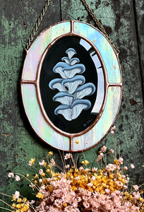 Blue oyster mushroom gouache painting on black. Oval shaped glass hanging wall art with oval rainbow iridized glass border and chain
