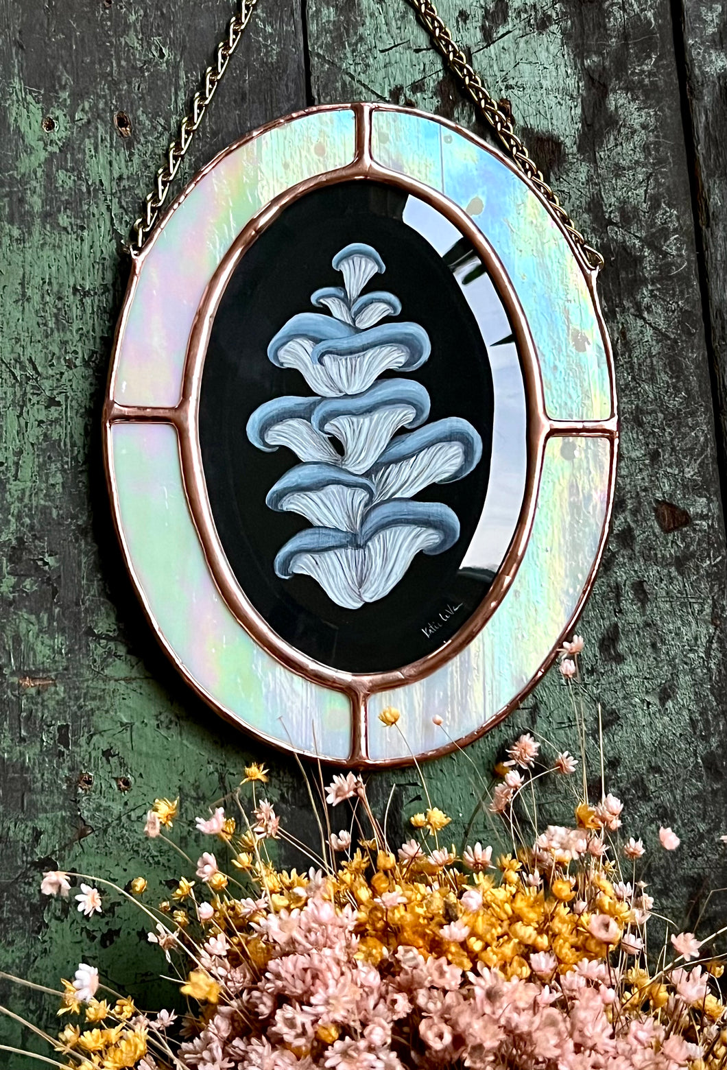 Blue oyster mushroom gouache painting on black. Oval shaped glass hanging wall art with oval rainbow iridized glass border and chain