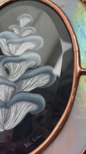 Load and play video in Gallery viewer, Video - showing close ups of all angles. Blue oyster mushroom gouache painting on black. Oval shaped glass hanging wall art with oval rainbow iridized glass border and chain
