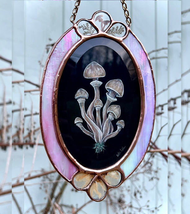 Full view of artwork - oval shape with three teardrop shaped glass pressed flower and mushroom inclusions at top and bottom of piece. Gouache and holographic powder on paper with pressed wild mushroom, fern, and cosmos flowers set between pink rainbow iridescent glass