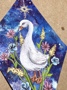 Painting only - White goose painting on blue dyed paper with pink, blue, and yellow flowers surrounding it at the base. Gold painted sun above goose. Diamond shape. Gouache painting on hand dyed paper in beveled glass.
