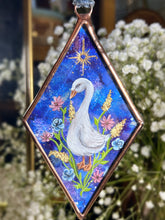 Load image into Gallery viewer, White goose painting on blue dyed paper with pink, blue, and yellow flowers surrounding it at the base. Gold painted sun above goose. Diamond shape. Gouache painting on hand dyed paper in beveled glass.
